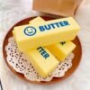 Hand holding a NeeDoh Butter Squishy realistic slow-rise butter stick toy — Image 9 of 11