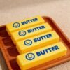 Hand holding a NeeDoh Butter Squishy realistic slow-rise butter stick toy — Image 11 of 11