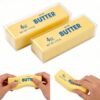 Hand holding a NeeDoh Butter Squishy realistic slow-rise butter stick toy — Image 1 of 11